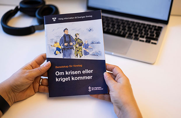 En person som håller i broschyren på ett skrivbord.