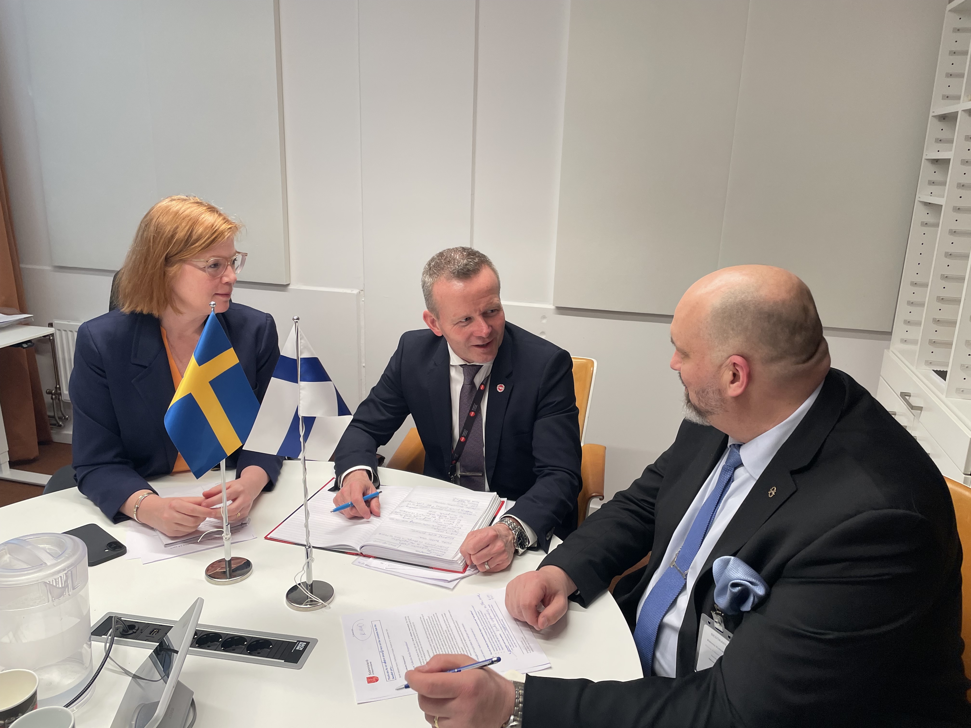 tre personer sitter vid ett bord