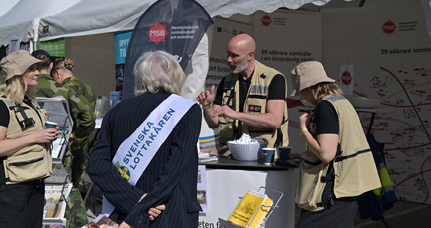 En man talar med en äldre kvinna vid ett utställningstält.