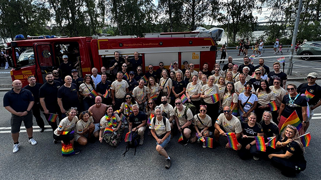 Gruppbild på alla som gick med i paraden från räddningstjänster och Myndigheten för civilt försvar framför en brandbil.