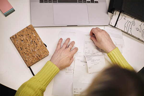 En kvinnas händer som grejar med kvitton på ett skrivbord