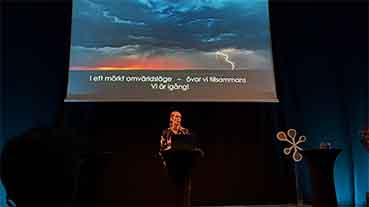 Projektledare Sofie Ivarsson står på en scen och beskriver scenariot från Övning av totalförsvar (ÖTF) under Mötesplats samhällsäkerhet.