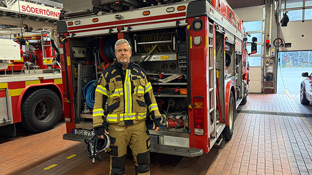 Man i utrustning framför en brandbil