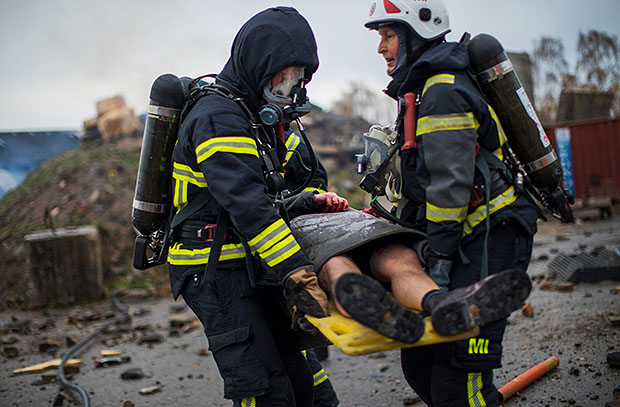 Brandmän bär en skadad person under en övning.