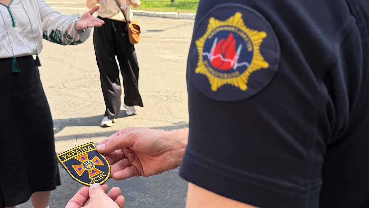 Person håller i en badge från ukrainska räddningstjänsten SESU.