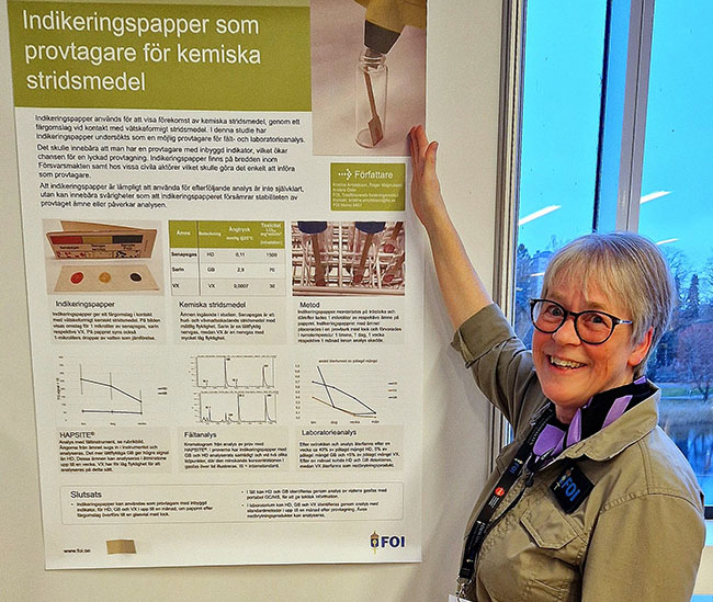 Em kvinna står framför ett bidrag i en posterutställning.