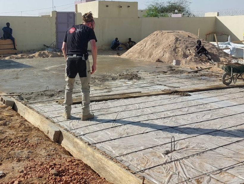 En man står och tittar på ett golv utomhus.